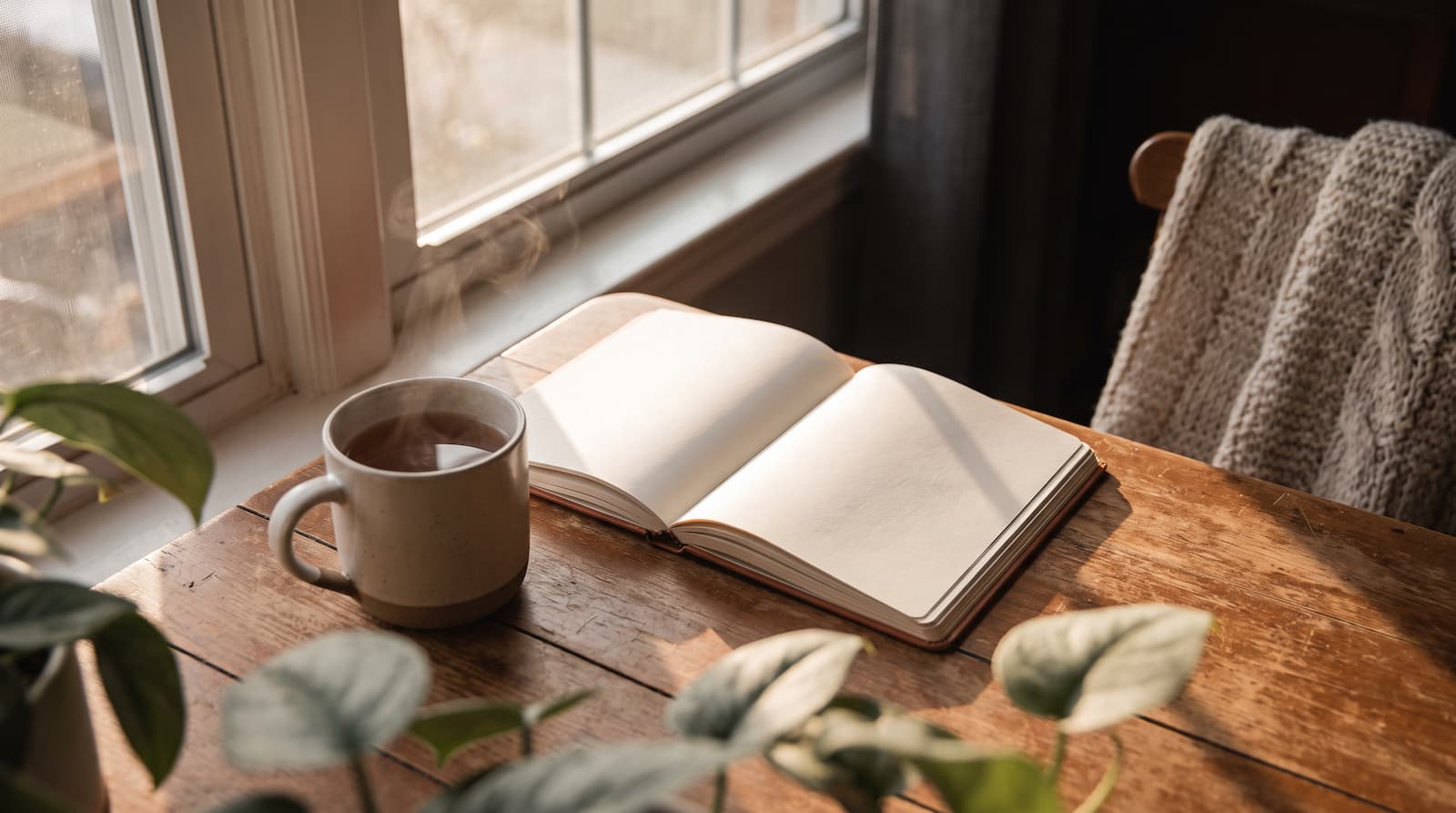 Open journal and cup of coffee on a table by a window