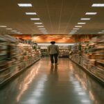 Blurred grocery store aisle with a lone man standing still, conveying the isolation of receiving a cancer diagnosis
